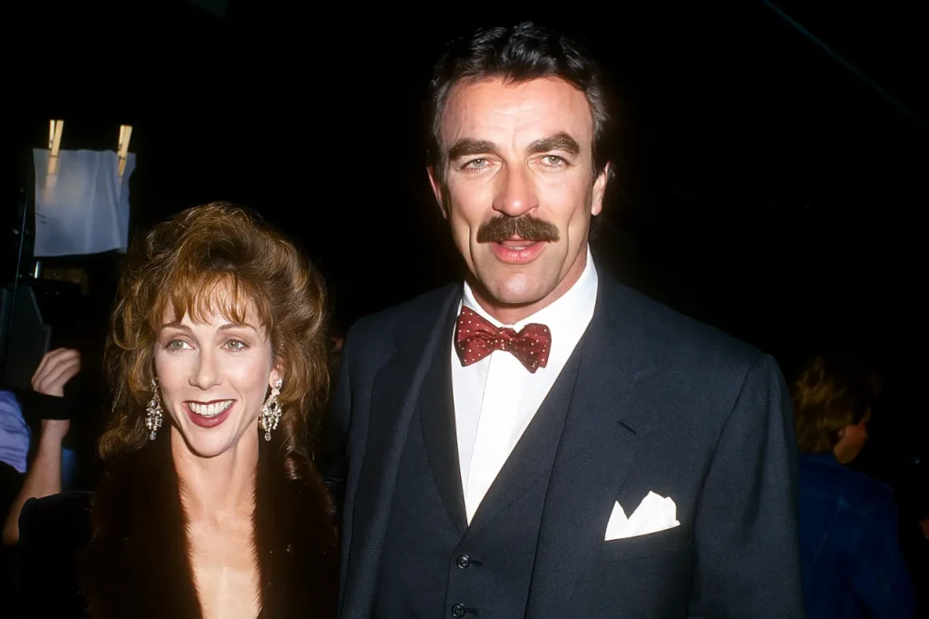 Tom Selleck and Jillie Mack smiling together at a formal Hollywood event, with a dark background and cinematic lighting.
