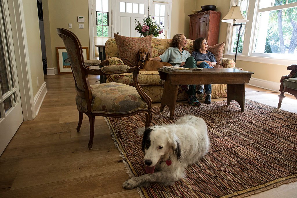 Linda Hunt and Karen Kline smiling in the living room of their craftsman-style bungalow.