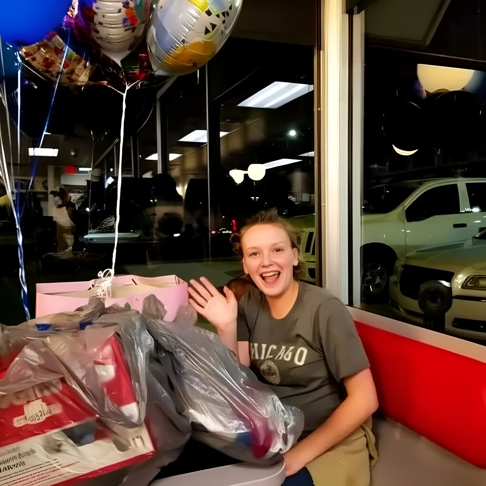 Hannah Hill smiling and waving while surrounded by gifts and balloons at Waffle House