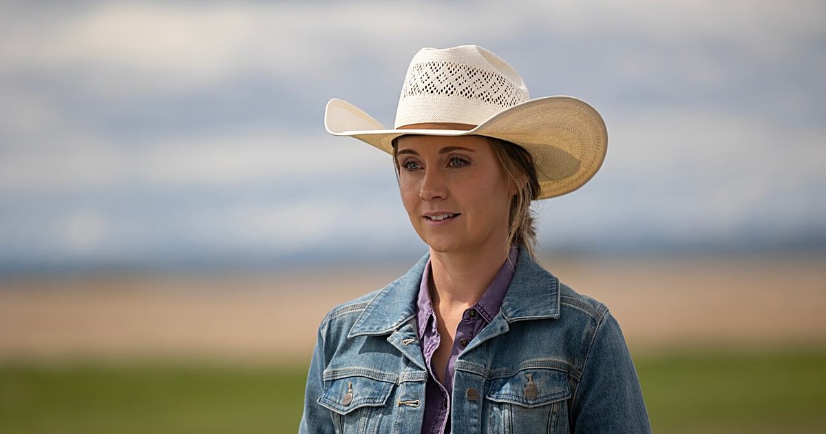 Amy Fleming (Amber Marshall) in a cream cowboy hat and denim jacket, looking off to the side on the Alberta prairie in Heartland