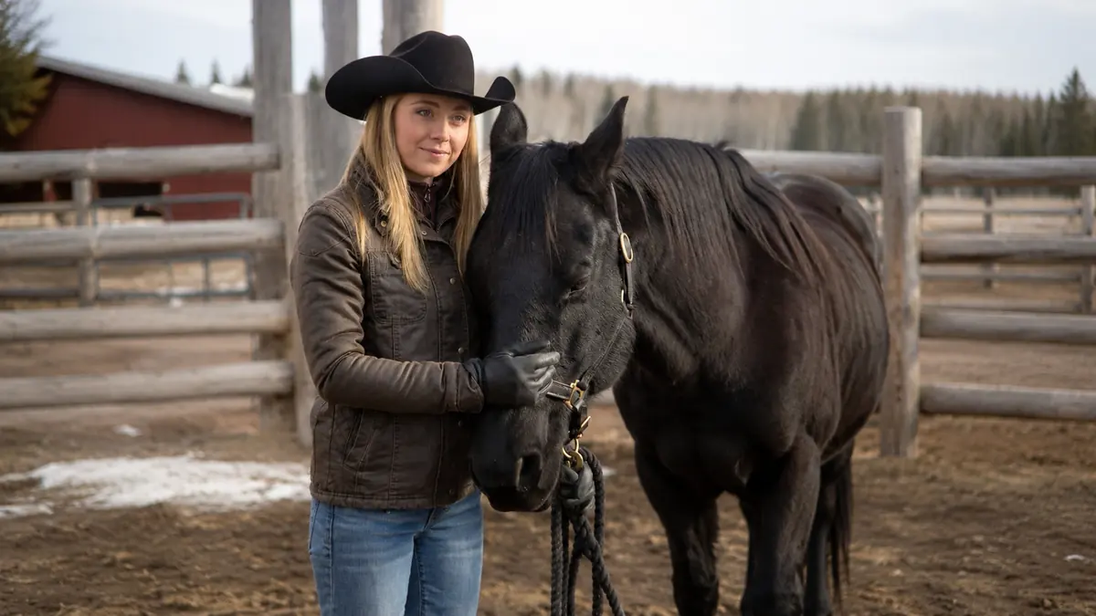 Amber Marshall smiling next to a horse on her ranch in Alberta